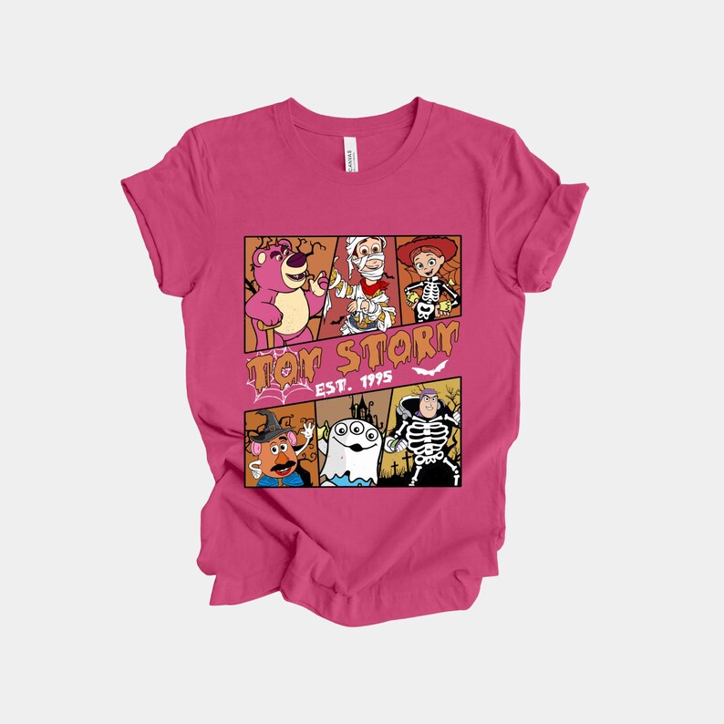 K&ouml;nnte beinhalten: Magentafarbenes T-Shirt mit einem Comic-Design von Toy Story-Charakteren in Halloween-Kost&uuml;men. Das Design zeigt Lotso, Woody und andere, mit dem Text "Toy Story EST. 1995".
