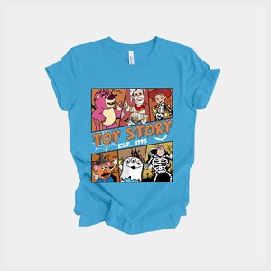 K&ouml;nnte beinhalten: Hellblaues T-Shirt mit einem Design aus dem Film Toy Story. Das Design zeigt Charaktere in Halloween-Kost&uuml;men, mit dem Text "Toy Story Est. 1995" in Orange. Das T-Shirt ist aus weichem Material.