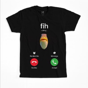 Puede incluir: Camiseta negra con un gráfico de una criatura abstracta y colorida en el centro. El texto "fih calling..." está encima de la criatura. Debajo hay círculos rojos y verdes con iconos de teléfono y las palabras "Decline" y "Accept".