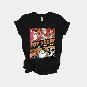 K&ouml;nnte beinhalten: Schwarzes T-Shirt mit einem farbenfrohen Grafikdesign von Toy Story-Charakteren in Halloween-Kost&uuml;men. Das Design zeigt Lotso, Woody und Buzz Lightyear, mit dem Text "Toy Story Est. 1995".