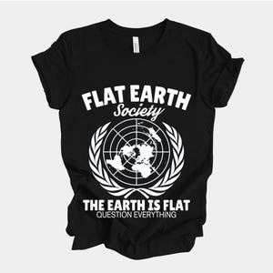 Puede incluir: Camiseta negra con el texto blanco "FLAT EARTH Society" sobre un gráfico del mapa mundial. Debajo del gráfico, el texto dice "THE EARTH IS FLAT QUESTION EVERYTHING". La camiseta tiene cuello redondo y mangas cortas.