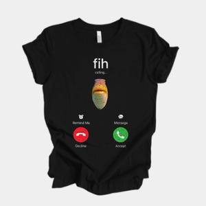 May include: Black t-shirt featuring a graphic of a fish with the text "fih calling...". The design includes a red decline button and a green accept button, resembling a phone call interface.