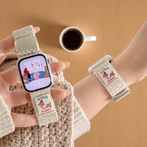 May include: A beige braided watch strap featuring a cartoon puppy design. The watch face shows a cartoon dog wearing a hat and a sweater. The strap has the words "NICEDAY" and "PUPPY" printed on it. A cup of coffee is also visible.