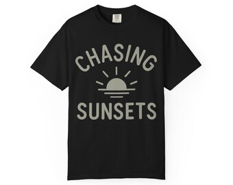 May include: Black t-shirt with the words "CHASING SUNSETS" in a light gray font. The design includes a sun graphic with rays. The shirt is a casual wear item.