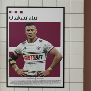 Könnte beinhalten: Poster mit Olakau'atu, einem Rugbyspieler, in einem weiß-weinroten Trikot mit dem Text "POINTSBET". Der Poster hat einen schwarzen Rahmen und hängt an einer gefliesten Wand. Der Spieler steht mit den Händen auf den Hüften.