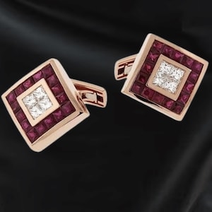 Puede incluir: Un par de gemelos de oro rosa con diseño cuadrado. Cada gemelo presenta un cuadrado central de piedras blancas rodeado por un cuadrado de piedras rojas. Sobre un fondo oscuro.