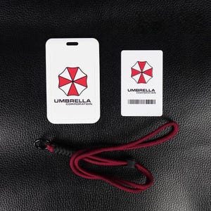 White Umbrella badge holder with inner card and red rope lanyard on leather background, cosplay ID case.