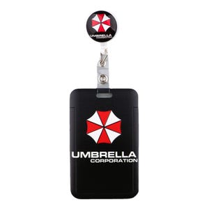 Umbrella Corporation badge reel and black ID holder closeup, red white umbrella logo work ID card protector.