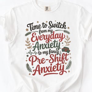 May include: White t-shirt with the text "Time to Switch from my Everyday Anxiety to my fancy Pre-Shift Anxiety" in black, red, and green. The design includes decorative floral elements.
