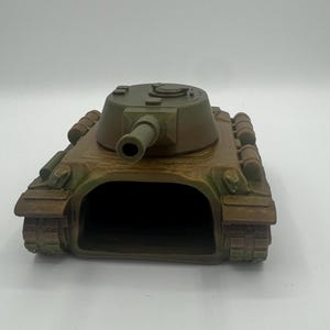 Peut inclure: Un char d'assaut jouet aux tons marron et vert, avec un design détaillé. Le char présente un canon proéminent, une tourelle arrondie et des détails de chenilles. C'est une réplique miniature d'un char militaire.