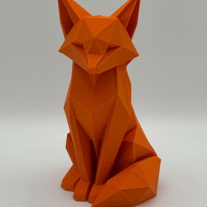 Könnte beinhalten: Eine leuchtend orangefarbene Fuchsfigur mit geometrischem Low-Poly-Design. Die Skulptur besteht aus mehreren flachen, dreieckigen Facetten, die die Form eines sitzenden Fuchses mit spitzen Ohren, einer scharfen Schnauze und einem Schwanz bilden.