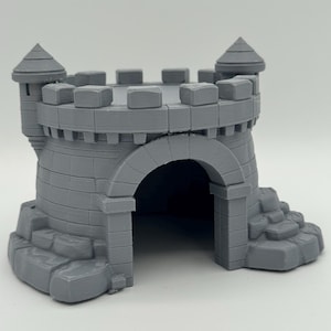 Peut inclure: Une structure de château gris imprimée en 3D présentant une porte centrale en arc, deux tours d'angle avec des toits coniques et un sommet de mur crénelé. La base de la structure est détaillée avec des textures et des marches en pierre.