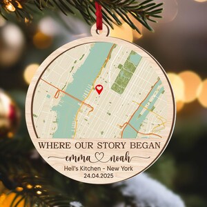 May include: A wooden Christmas ornament with a map of New York City, featuring a red heart marker. The ornament has the text "WHERE OUR STORY BEGAN" and the names "emma ♡ noah", along with "Hell's Kitchen - New York 24.04.2025".