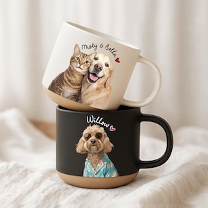 May include: Two ceramic mugs stacked on top of each other. The top mug is white with a tan base and features a cat and dog with the text "misty & Bella". The bottom mug is black with a tan base and features a dog wearing sunglasses with the text "Willow".