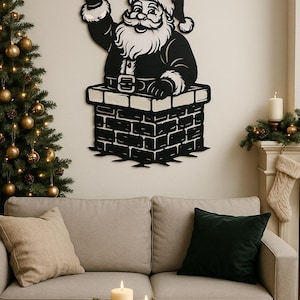Può includere: Decorazione da parete in metallo nero di Babbo Natale che esce da un camino di mattoni, che saluta. L'addobbo festivo è sopra un divano grigio, con un albero di Natale e candele sullo sfondo. Un accogliente oggetto di arredamento natalizio.
