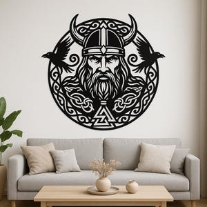 Puede incluir: Arte mural de metal negro que representa a un guerrero vikingo con casco con cuernos, barba larga y dos cuervos. La obra de arte circular presenta intrincados nudos celtas y formas geométricas.