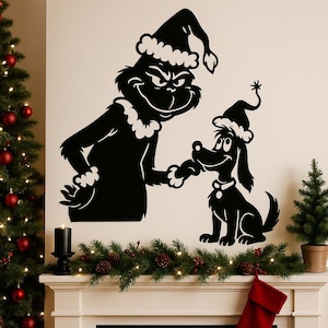 Puede incluir: Arte mural de silueta negra que representa al Grinch y su perro, ambos con gorros de Papá Noel. El Grinch extiende su mano al perro. La imagen está colocada contra una pared neutra, con una repisa decorada debajo.