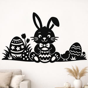 Puede incluir: Arte mural de Pascua en silueta negra con un conejito con pajarita, sosteniendo un huevo de Pascua. El diseño incluye huevos decorativos, hierba y un pollito. Decoración festiva.
