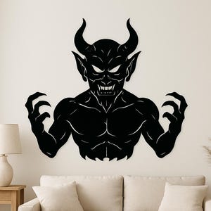 May include: A black wall art piece depicting a demonic figure with horns, sharp teeth, and clawed hands. The artwork is a silhouette, with white highlights defining the facial features and muscular physique. The figure is posed with arms outstretched.