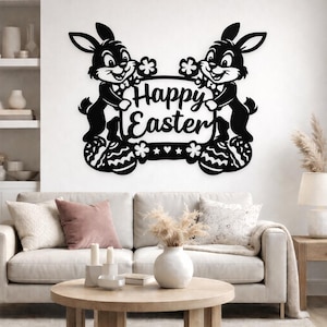May include: Black metal Easter wall art featuring two cartoon bunnies holding a sign that reads "Happy Easter." The bunnies stand on decorated Easter eggs. The art is mounted on a white wall above a sofa.