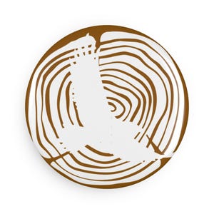 May include: A round, brown and white decorative plate with a tree ring design. The plate features a white silhouette of a bird in flight. The plate is a decorative item.