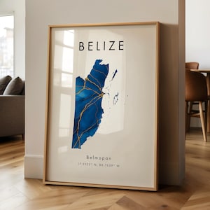 Puede incluir: Impresión artística enmarcada que presenta un mapa de Belice con un diseño azul y dorado. La palabra "BELIZE" está impresa en la parte superior, con "Belmopán" y las coordenadas debajo. La impresión está en un marco de madera clara.