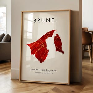 Può includere: Stampa artistica incorniciata con una mappa rossa e oro del Brunei. La parola "BRUNEI" è stampata in nero in alto, con "Bandar Seri Begawan" e le coordinate sottostanti. L'opera d'arte è esposta in una stanza con pavimento in legno.