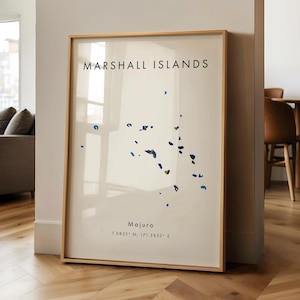 Puede incluir: Impresión enmarcada de las Islas Marshall. La obra presenta un fondo crema con un mapa azul de las islas. El texto "Marshall Islands" está en la parte superior, con "Majuro" y las coordenadas en la parte inferior. El marco es de madera clara.