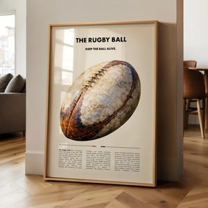 Könnte beinhalten: Gerahmter Druck mit einem Rugbyball im Vintage-Stil. Der Text „THE RUGBY BALL“ und „KEEP THE BALL ALIVE“ sind oben zu sehen. Der Ball ist braun, weiß und beige, mit sichtbaren Nähten und einem Used-Look.