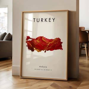Könnte beinhalten: Gerahmter Kunstdruck mit einer Aquarellkarte der Türkei in Rot- und Goldtönen. Das Wort "TURKEY" ist oben aufgedruckt, darunter "Ankara" und Koordinaten. Der Druck ist in einem Holzrahmen ausgestellt.