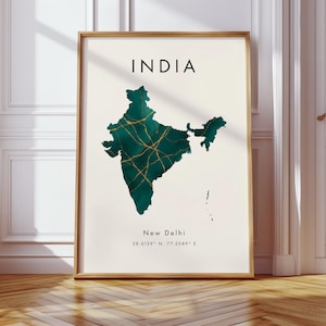 Może przedstawiać: Oprawiony wydruk przedstawiający mapę Indii w kolorze morskim i złotym na kremowym tle. U góry napis "INDIA", poniżej "New Delhi" i współrzędne. Wydruk jest w drewnianej ramie.