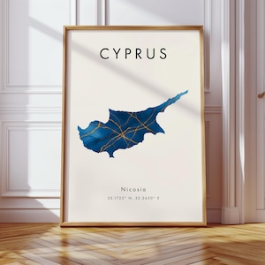 Puede incluir: Un cuadro enmarcado con la palabra "CYPRUS" en la parte superior. El cuadro muestra un mapa azul y dorado de Chipre sobre un fondo crema. La ciudad de Nicosia y sus coordenadas se enumeran debajo.
