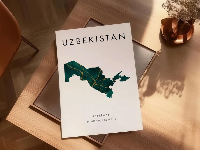 Pu&ograve; includere: Una stampa bianca con la parola "UZBEKISTAN" in nero e una mappa verde e oro dell'Uzbekistan. La stampa include anche la citt&agrave; di "Tashkent" e le coordinate. La stampa &egrave; esposta su un tavolo di legno.