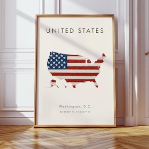 Può includere: Una stampa incorniciata raffigurante una mappa degli Stati Uniti, con il design della bandiera americana sovrapposto. La stampa include il testo "UNITED STATES" in alto e "Washington, D.C." con le coordinate in basso. La cornice è di colore marrone chiaro.