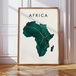 Pode incluir: Uma impressão artística emoldurada com um mapa da África em tons de verde-azulado e dourado. A palavra "AFRICA" está impressa em preto no topo. A obra de arte está sobre um fundo creme, com uma moldura de madeira.