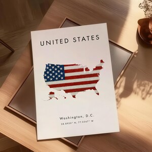 Może przedstawiać: Biały nadruk przedstawiający mapę Stan&oacute;w Zjednoczonych z motywem amerykańskiej flagi. U g&oacute;ry znajduje się napis &bdquo;UNITED STATES&rdquo;, a na dole &bdquo;Washington, D.C.&rdquo; ze wsp&oacute;łrzędnymi. Nadruk znajduje się na drewnianym stole.