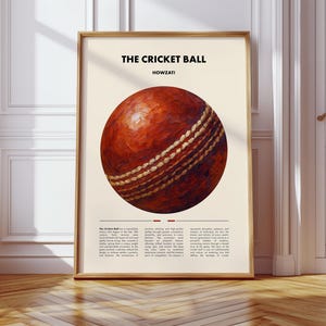 Puede incluir: Impresión enmarcada que presenta una ilustración detallada de una pelota de críquet. La pelota es de un rico marrón rojizo texturizado con costuras blancas. El texto "THE CRICKET BALL" y "HOWZAT!" se muestran encima de la pelota. La impresión está en un marco de madera.