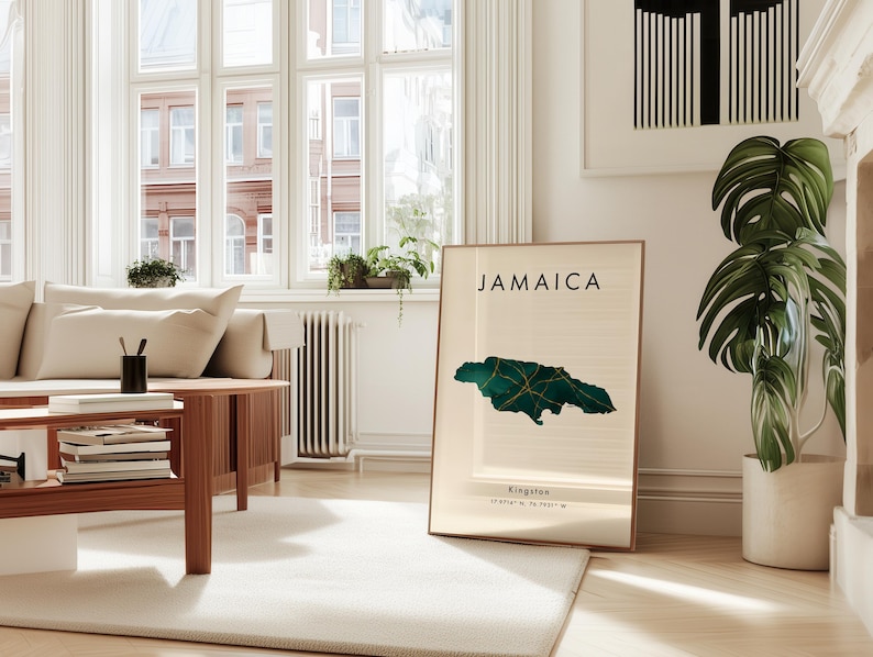 May include: A framed print displaying the word "JAMAICA" above a green and gold map of Jamaica. The print is in a light-filled room with a white rug and wooden furniture. The print also includes the city of Kingston and its coordinates.