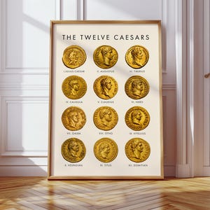 May include: Framed print featuring "THE TWELVE CAESARS" with gold-colored coin illustrations. Each coin displays a profile of a Roman emperor, with names below. The print is in a wooden frame, set against a cream background.