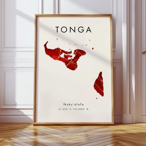May include: Framed art print showing a map of Tonga in red and gold. The word "TONGA" is printed in black at the top, with "Nuku'alofa" and coordinates below. The artwork is set against a cream background, in a wooden frame.