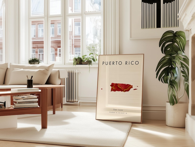 May include: A framed print with the words "PUERTO RICO" and a red and gold map of the island. Below the map are the words "San Juan" and coordinates. The print is in a bright, modern living room.