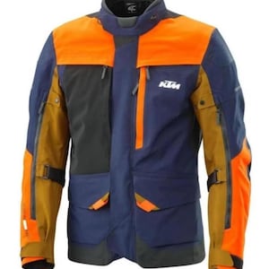 Puede incluir: Chaqueta de moto en azul, naranja y marrón. La chaqueta tiene múltiples bolsillos, cremalleras y el logotipo de KTM. Tiene un cuello alto y está diseñada para la protección y la visibilidad. La chaqueta es de talla mediana.