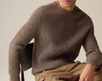 May include: A brown ribbed knit sweater with a crew neck. The sweater has a textured appearance and is made of a soft material. The model is wearing brown cargo pants. The sweater is a classic style.