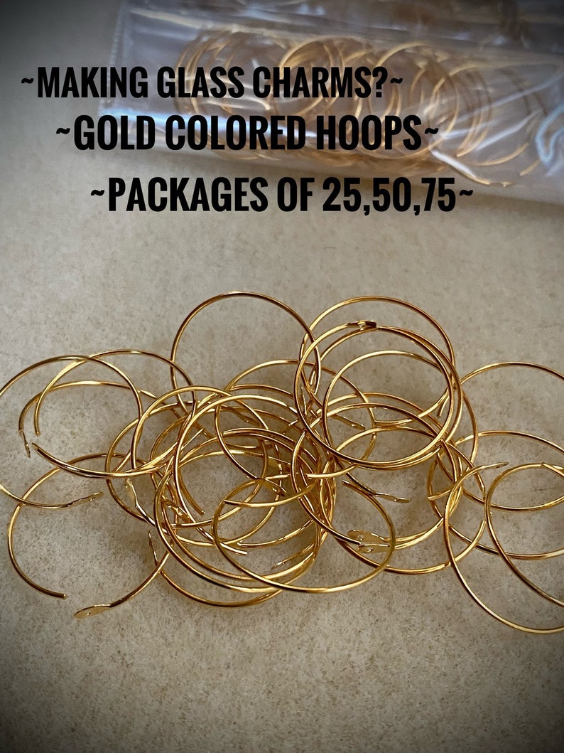 Op de afbeelding: Een stapel gouden metalen hoepels, ideaal voor het maken van glazen bedels. De tekst op de afbeelding luidt "~MAKING GLASS CHARMS?~ ~GOLD COLORED HOOPS~ ~PACKAGES OF 25,50,75~"