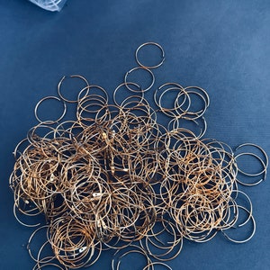 Op de afbeelding: Een grote stapel gouden metalen hoepels of ringen op een donkerblauwe achtergrond.
