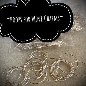 Op de afbeelding: Een close-up van een zak met zilveren metalen hoepels voor wijncharms. De zak is gelabeld met "HOOPS FOR WINE CHARMS".