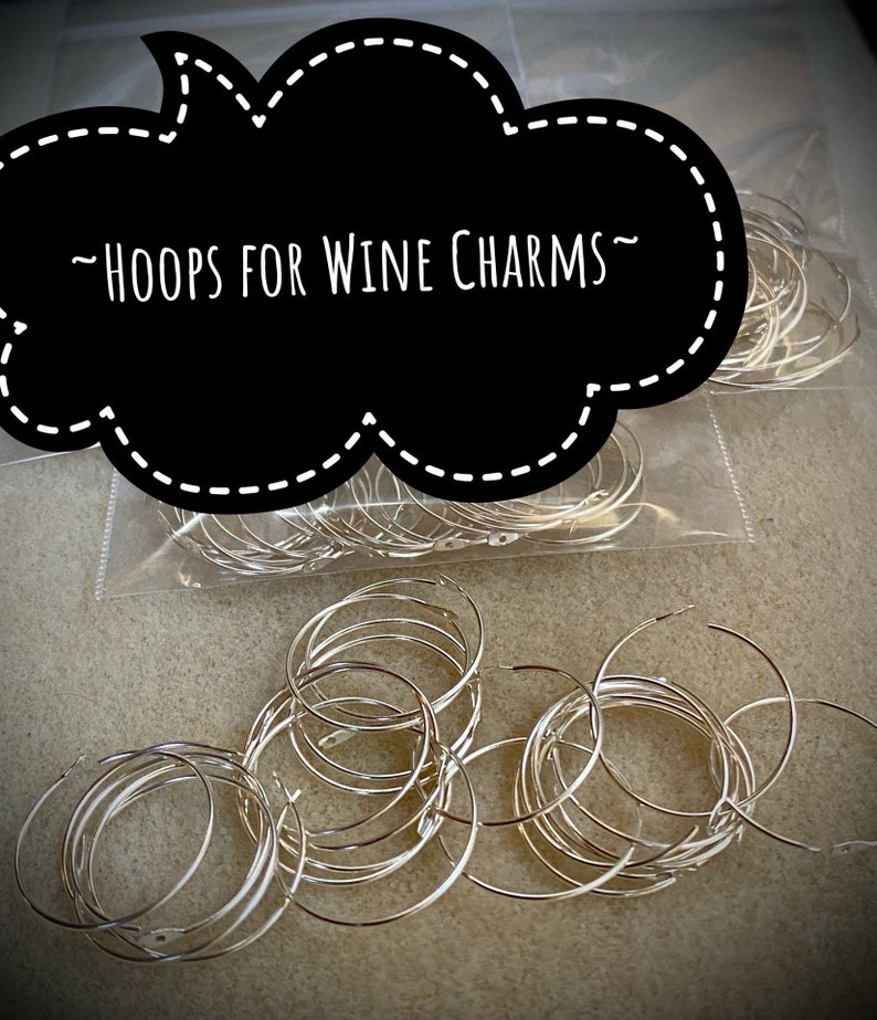 Op de afbeelding: Een close-up van een zak met zilveren metalen hoepels voor wijncharms. De zak is gelabeld met "HOOPS FOR WINE CHARMS".