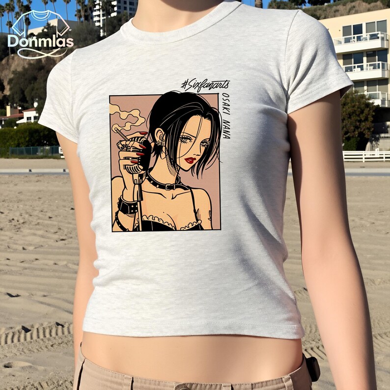 Puede incluir: Camiseta gris claro con una ilustraci&oacute;n de estilo manga de una mujer sosteniendo un micr&oacute;fono. La ilustraci&oacute;n incluye el texto "#Sexypants" y "OSAKI NANA". La mujer tiene cabello negro, l&aacute;piz labial rojo y usa un collar&iacute;n y una pulsera negros.