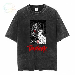May include: Dark grey t-shirt with a graphic print of a character with a helmet and the word "Berserk" in red. The design is a black and white illustration with a red eye. The shirt has a faded, washed appearance.