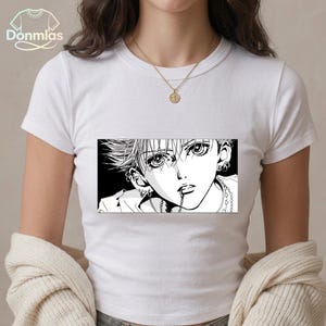 May include: White t-shirt featuring a black and white manga-style graphic of a person with multiple piercings and a chain. The graphic is rectangular and centered on the shirt. The shirt has short sleeves and a crew neck.